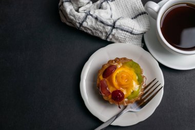 Portakal kiraz ve kivi ile dekore edilmiş siyah kahve ve meyve tart ile lezzetli tatlı