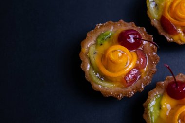 Siyah arka plan üzerinde turuncu kivi ve kiraz ile ev yapımı meyve tart