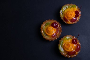 Siyah arka plan üzerinde turuncu kivi ve kiraz ile ev yapımı meyve tart