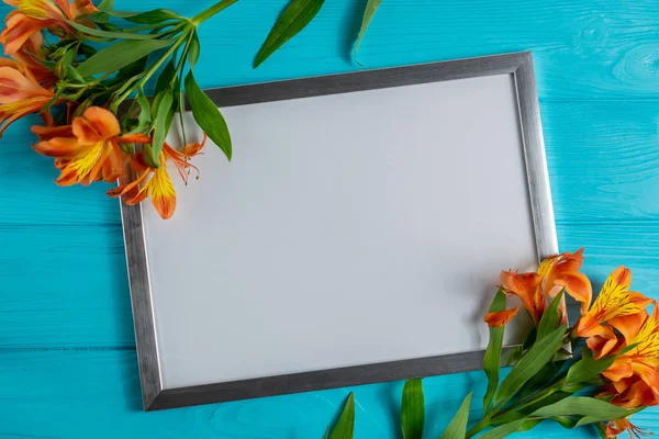 White frame mock up with copy space for text on blue wooden background with alstroemeria flowers
