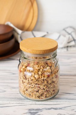 Mutfakta ahşap masa üzerinde cam kavanozda ev yapımı granola