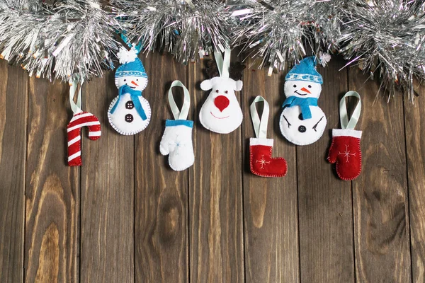 Buntes Weihnachtsspielzeug aus Filz und silbernes Lametta auf Holzgrund — Stockfoto
