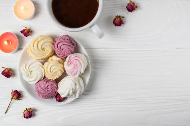 Beyaz bir tabakta farklı aromalı mini marşmelovlar ve bir fincan sıcak çikolata.