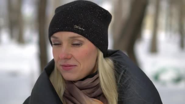 Jeune fille heureuse en manteau de fourrure noire soufflant sur la neige dans le parc. Vacances d'hiver. Portrait de fille heureuse dans le parc d'hiver, elle joue avec la neige . — Video