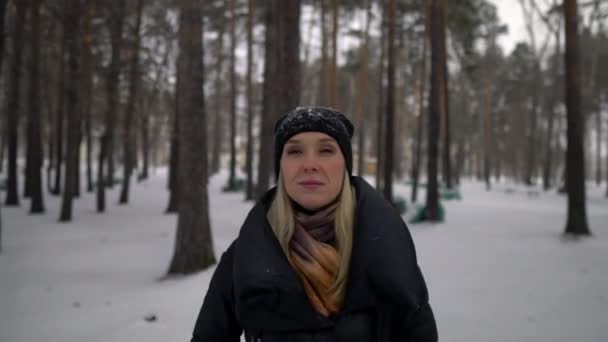 Šťastná dívka v černém kožichu foukání na sněhu v parku. Zimní dovolená. Portrét šťastná dívka v zimě parku, hraje se sněhem. — Stock video