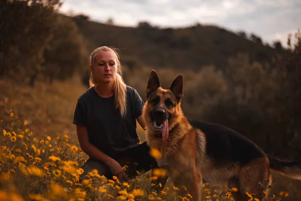 Blondes Mädchen spielt mit Schäferhund in einem Feld aus gelben Blumen — Stockfoto