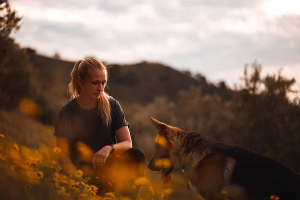 Blondes Mädchen spielt mit Schäferhund in einem Feld aus gelben Blumen — Stockfoto