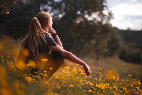 금발의 소녀 앉아 에 이 분야 의 노란 꽃 스톡 이미지