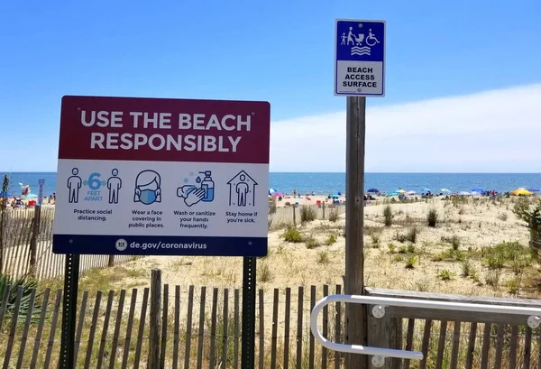 Rehoboth Beach, Delaware, ABD - 13 Haziran 2020 - Tahta kaldırımda yazan tabela ziyaretçilere maske takmalarını, düzenli olarak sterilize olmalarını ve sosyal mesafeyi ölçmelerini tavsiye ediyor.