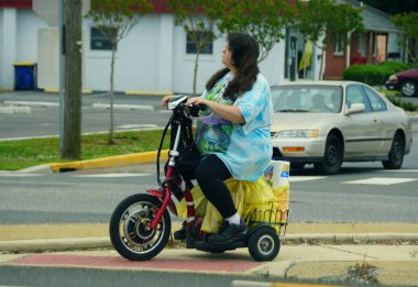 İzmir, Delaware, ABD - 4 Temmuz 2020 Sokakta scooterıyla gezen bir kadın