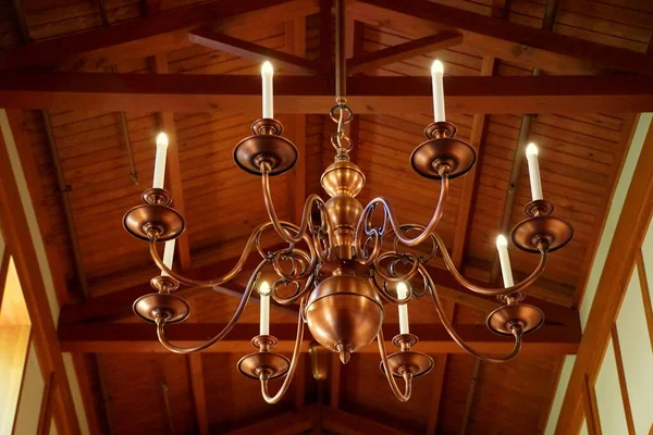 A large copper chandelier hanging on the wooden ceiling