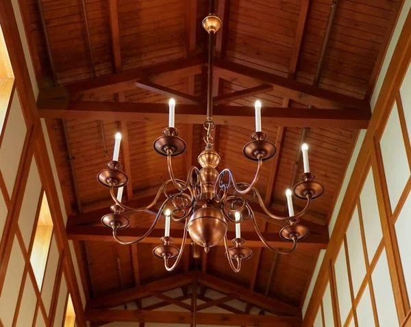 A large copper chandelier hanging on the wooden ceiling