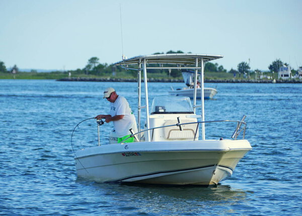 Bethany Beach, Делавэр, США - August 1, 2020 - A man reeling a big fish on the boat near Indian River Inlet