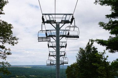 Boş sandalyeler, Kamelback Dağı, Tannersville, Pennsylvania, ABD yakınlarındaki sıcak bir yaz mevsiminde sık bir orman gölgesinden yükselirler..