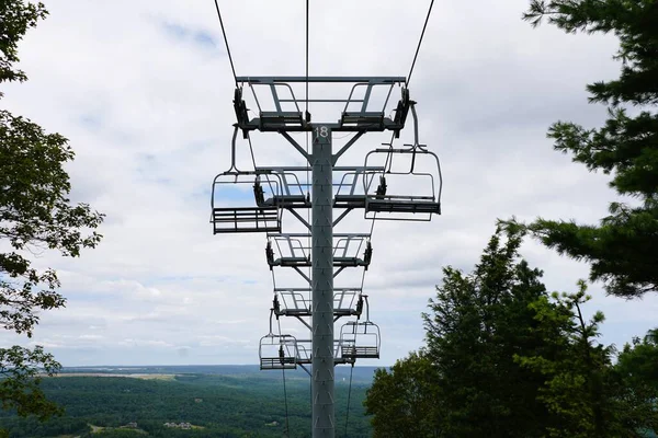 Boş sandalyeler, Kamelback Dağı, Tannersville, Pennsylvania, ABD yakınlarındaki sıcak bir yaz mevsiminde sık bir orman gölgesinden yükselirler..