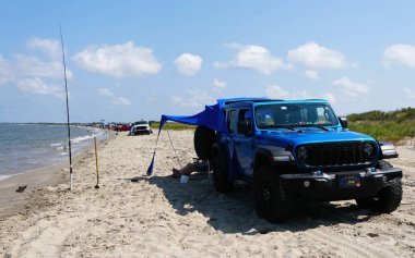 Milton, Delaware, U.S.A - Sept 2, 2025 - A blue Jeep Wrangler with a tent by the ocean near Beach Plum Nature Preserve