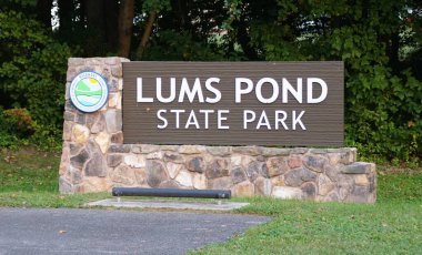 Newark, Delaware, U.S.A - Sept 14, 2025 - Lums Pond State Park entrance sign features Delaware State Parks emblem; set in lush greenery, welcoming visitors