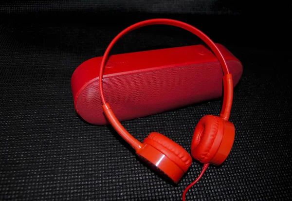 red headphones and music speaker on a black background