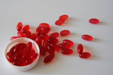 Beyaz arka planda ve kapaklı kırmızı oval haplar