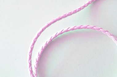 beyaz bir arka plan üzerinde pembe deri ince örgülü bilezik 