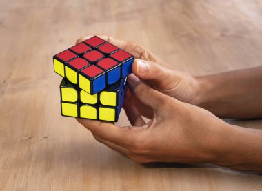 Berlin, Almanya; 9 Şubat 2019: Rubik küp zeka oyuncak çözme ve elinde tutma, ahşap bir masada
