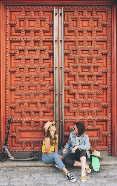Mladé ženy gayové pár hledá a usmívá se navzájem v červených dveřích pozadí. Stejné sexuální štěstí a radostný koncept. — Stock fotografie