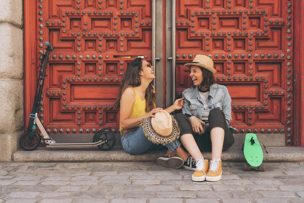 Junge schwule Frauen, die einander vor rotem Türhintergrund anschauen und lächeln. Gleichgeschlechtliches Glück und freudiges Konzept. — Stockfoto