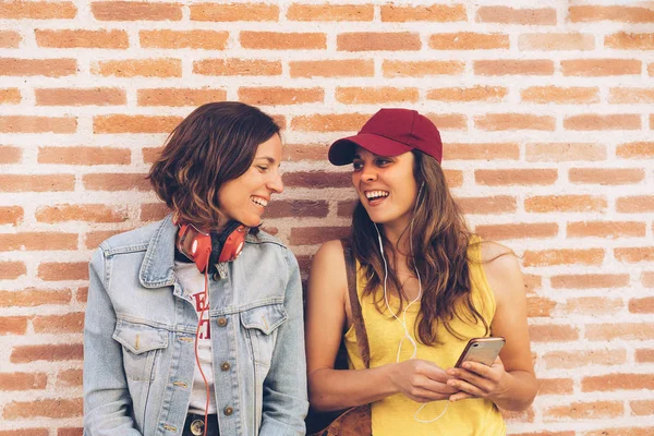 Giovani donne coppia guardando e sorridendo l'un l'altro in un muro di mattoni sfondo. Stesso sesso felicità e scena gioiosa . — Foto Stock