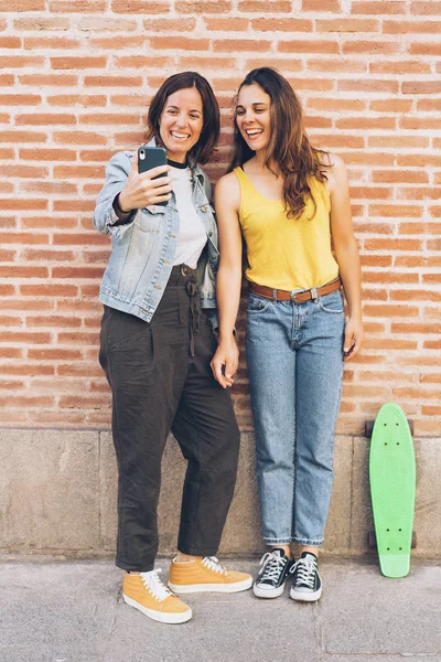Giovani donne che si fanno un selfie. Dietro un muro di mattoni. Emozione positiva e concetto di tolleranza . — Foto Stock