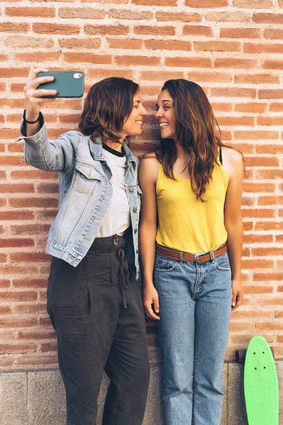 Mladé ženy dělají selfie. Za cihlovou zdí. Pozitivní koncepce emocí a tolerance. — Stock fotografie