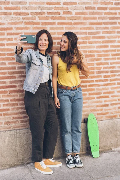 Giovani donne che si fanno un selfie. Dietro un muro di mattoni. Emozione positiva e concetto di tolleranza . — Foto Stock