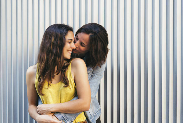 Affectionate woman kissing her happy girlfriend smiling, same sex relationship concept.
