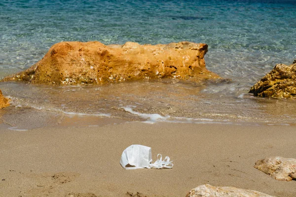 Beach polluted with face mask of covid. Environmental contamination problem