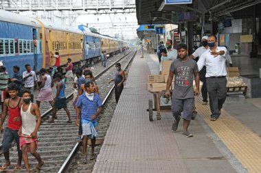 Burdwan, Batı Bengal / Hindistan - 30.05.2020: COVID-19 durumunun ortaya çıkmasından dolayı diğer eyaletlerde mahsur kalan göçmen işçiler evlerine dönerken demiryolu bölümü tarafından ücretsiz yiyecek veriliyor. Burdwan Junction Tren İstasyonunda.