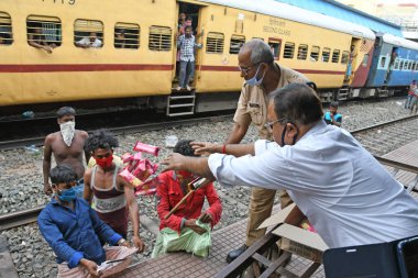 Burdwan, Batı Bengal / Hindistan - 30.05.2020: COVID-19 durumunun ortaya çıkmasından dolayı diğer eyaletlerde mahsur kalan göçmen işçiler evlerine dönerken demiryolu bölümü tarafından ücretsiz yiyecek veriliyor. Burdwan Junction Tren İstasyonunda.