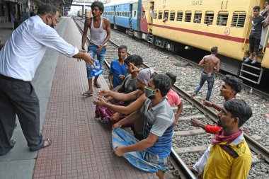 Burdwan, Batı Bengal / Hindistan - 30.05.2020: COVID-19 durumunun ortaya çıkmasından dolayı diğer eyaletlerde mahsur kalan göçmen işçiler evlerine dönerken demiryolu bölümü tarafından ücretsiz yiyecek veriliyor. Burdwan Junction Tren İstasyonunda.