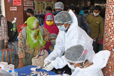 Burdwan, Batı Bengal / Hindistan - 29,05.2020: COVID-19 'un ortaya çıkması nedeniyle başka bir eyalette mahsur kalan göçmen işçiler ve ailelerine sağlık görevlileri tarafından kendi devletlerine döndükten sonra hidroklorokin tabletleri veriliyor.