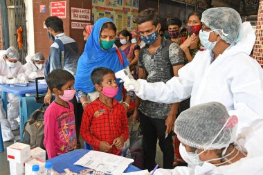 Burdwan Town, Purba Bardhaman, Batı Bengal / Hindistan - 29.05.2020: Diğer eyaletlerden gelen 'Shramik Special' treniyle memleketlerine dönen göçmen işçiler Roman Coronavirus (COVID-19) için sağlık taraması yapılıyor. 