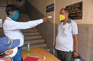 Burdwan Town, Purba Bardhaman İlçesi, Batı Bengal / Hindistan - 13.07.2020: Purba Bardhaman Zilla Parishad 'a gelen insanlar, COVID-19 enfeksiyonunu önlemek için hijyen kurallarına (Termal Tarama ve El Temizleme) uyarak içeri giriyorlar.