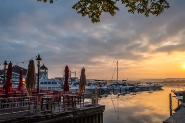 Boats on the Potomac River in Alexandria Virginia, just outside of District of Columbia, Washington DC, USA. Beautiful colors in the sunrise sky. Calm waters in the early morning, sailboats rest in the harbor, row boats, oars wait silently clipart