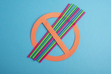 Plastik yok. Renkli plastik saman bir sürü mavi bir arka plan üzerinde kırmızı bir yasaklama daire içinde kurulmuş, bir çevre konsepti için yasağı bir kampanya söylüyorum. Metin için alan kopyalama.