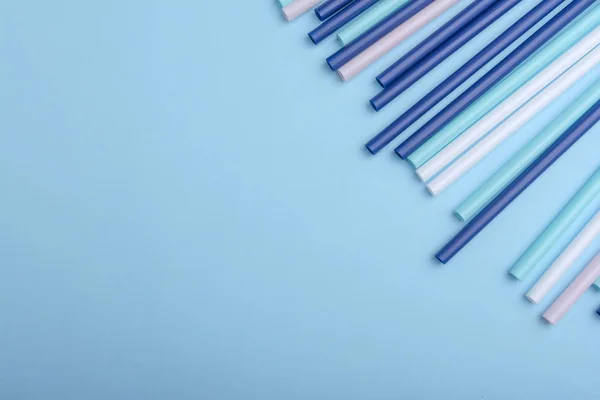 Tubos de plástico pode usar como fundo em design. Palhinhas de coquetel multicoloridas deitadas em um fundo azul com espaço de cópia para texto. Vista superior . — Fotografia de Stock