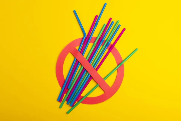 Un coloré de pailles en plastique utilisé pour l'eau potable ou les boissons gazeuses. Concept de protestation. Pas de plastique sur fond jaune. Espace de copie pour le texte . — Photo