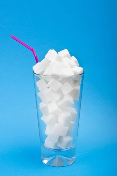 Napoje kaloryczne. Dużo cukru w energii. Biały cukier w szklance na niebieskim bsckground. Układ pionowy. — Zdjęcie stockowe