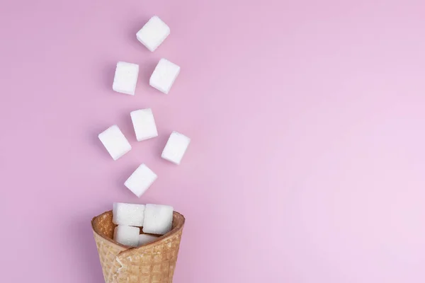 Cone de sorvete com cubos de açúcar em fundo rosa brilhante. Conceito mínimo de comida. Copiar espaço para texto. Vista superior . — Fotografia de Stock