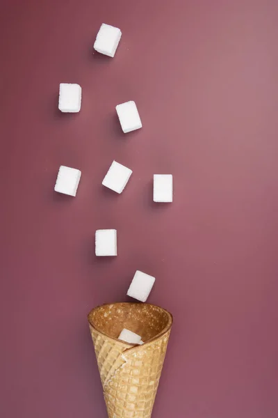 Koncepcja cukru. Latające kostki cukru z lodów stożek na czerwonym tle. Skopiuj miejsce na tekst. Widok z góry. Układ pionowy. — Zdjęcie stockowe