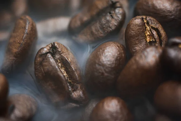 Roasted coffee beans with smoke. Coffee Background.