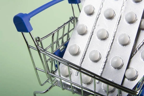 Alışveriş arabasında haplar. Makro. Mini alışveriş sepetinde çeşitli tabletler ve ilaçlar bulunmaktadır. Medecine kavramı.