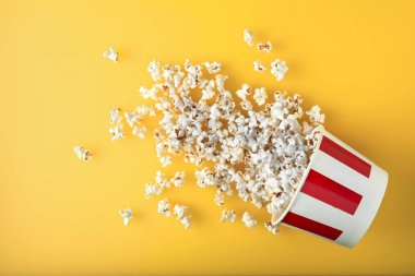 Sarı arka plan üzerinde patlamış mısır ile Dağınık kağıt Kupası. Taze patlamış mısır. Online film izlemek için harika bir atıştırmalık.