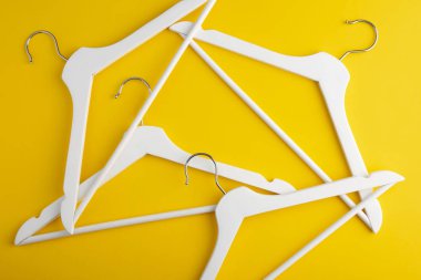Sarı arka planda beyaz elbise askısı. Mağaza konsepti, satış, tasarım, boş askı. Moda konsepti. Boş elbise askısı stoku. Düz yatıyordu